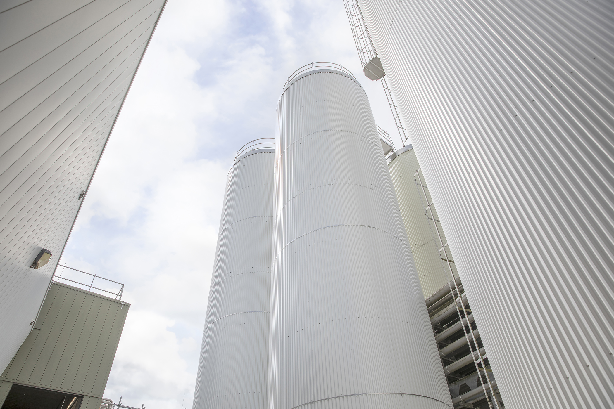 Large industrial plant at FrieslandCampina Gerkesklooster, featuring numerous pipes and stainless steel storage tanks under a clear sky.