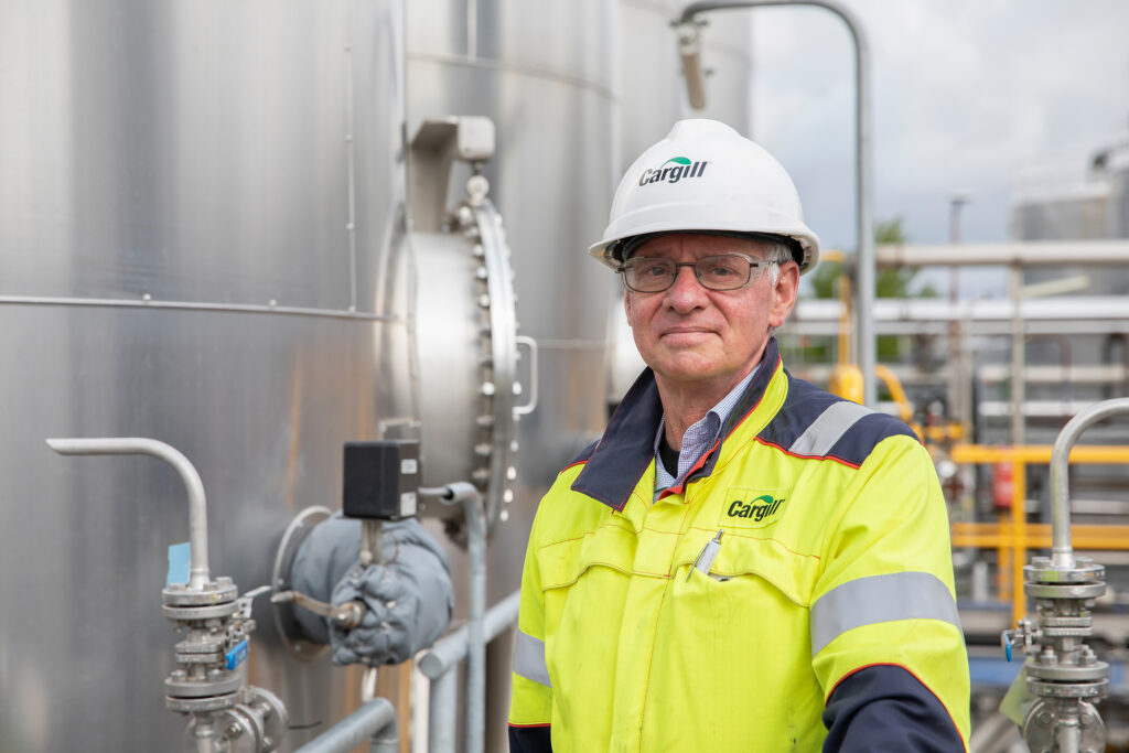 Jan de Jong, mechanical engineer at Cargill Gouda, standing beside a large industrial tank while wearing a safety vest.