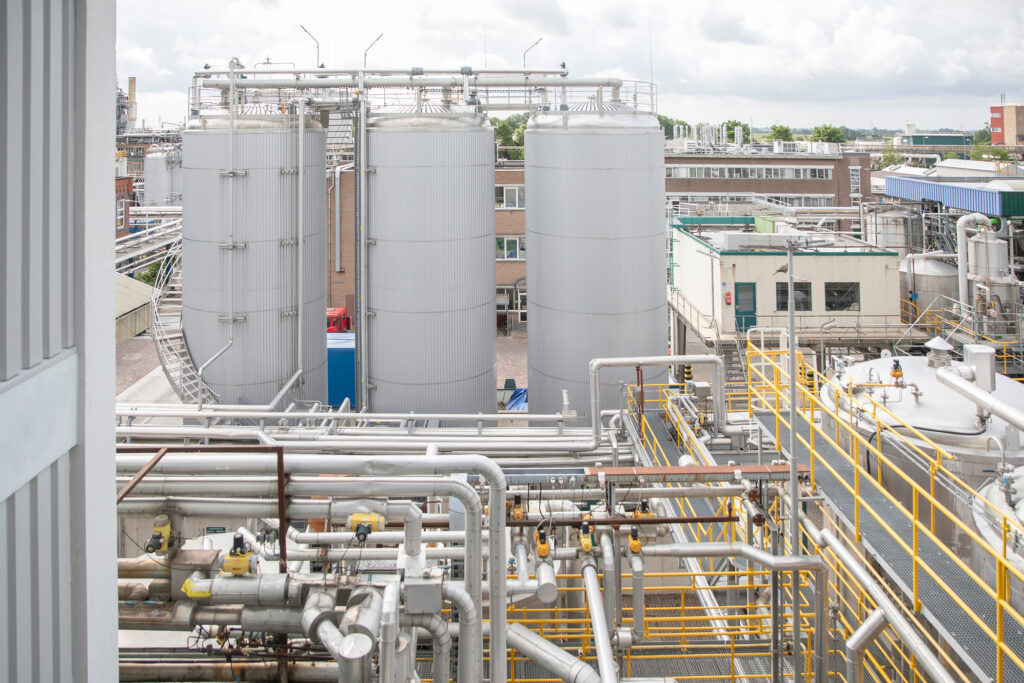 A large industrial plant with interconnected stainless steel pipes and storage tanks, highlighting complex industrial infrastructure.